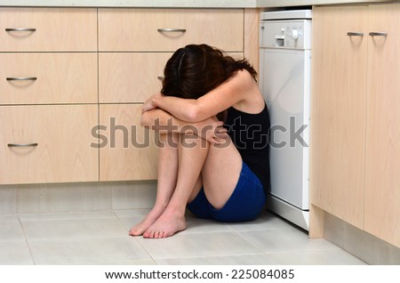 Sad woman sit in her kitchen and covering her face after domestic violence