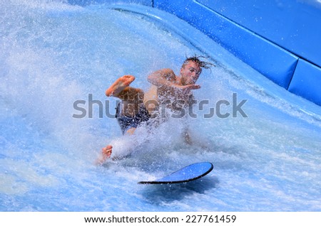 GOLD COAST OCT 29 2014: Man falling from a surfing board on FlowRider. It is a water park attraction that simulate the riding of waves in the ocean