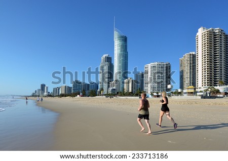 SURFERS PARADISE - NOV 08 2014:Couple runs on the beach in Surfers Paradise.It one of Australia\'s iconic coastal tourist destinations, drawing 10 million tourists every year from all over the world.