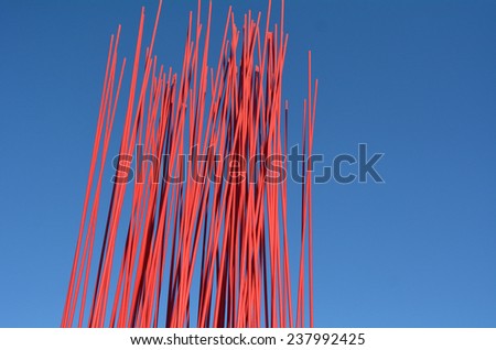 Red metal poles against blue sky. Abstract texture background.