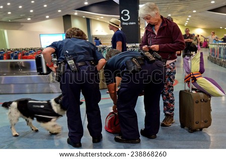 AUCKLAND, NZL - NOV 22 2014:Biosecurity officers with sniffer dog on duty.New Zealand has very strict biosecurity procedures at airports and ports to prevent the introduction of pests and diseases.