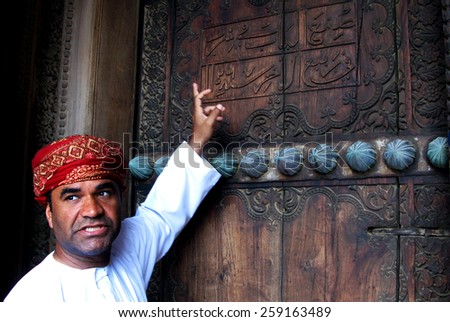 RUSTAQ, OMAN - DEC 23 2007:Omani tour guide explain the meaning of Arab words on the gate of Al Hazm Fort.Arabic is a Semitic language, date back to AD 512-568 closely related to Aramaic and Hebrew.