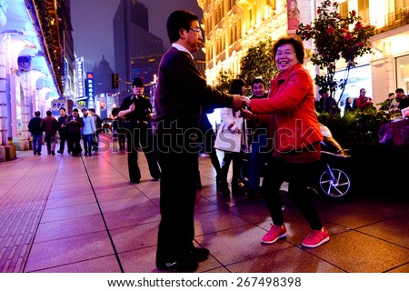 SHANGHAI, CN - MAR 17 2015:Elderly Chines couple dance at Nanjing Road. It is the main shopping street of Shanghai, China, and is one of the world\'s busiest shopping streets.