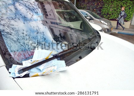 TEL AVIV - APR 02 2015:Parking tickets under windshield wiper of a car.With just 35,000 legal parking spots and 500,000 cars coming to Tel Aviv every day about 840,000 parking tickets issued a year.