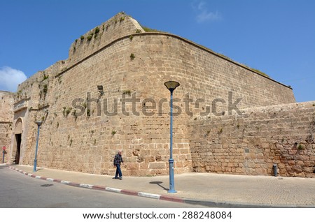 ACRE, ISRAEL - APR 21 2015: Arab man walks under the walls of Akko.Old Acre is one of the few cities in the world whose walls have remained standing despite attacks by large powerful armies several times