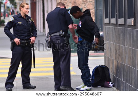 SAN FRANCISCO - MAY 15 2015:SFPD officers patdown black american man in San Francisco.Overall, Black Americans are arrested at 2.6 times the per-capita rate of all other Americans.