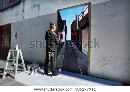 AUCKLAND - AUG 01 2015:Graffiti artist paint a mural on a wall.Graffiti is controversial amongst city officials, law enforcement and artists who wish to create and display artwork in public locations.