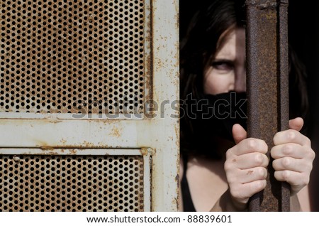 A woman trapped in a prison jail cell with a mouth cover
