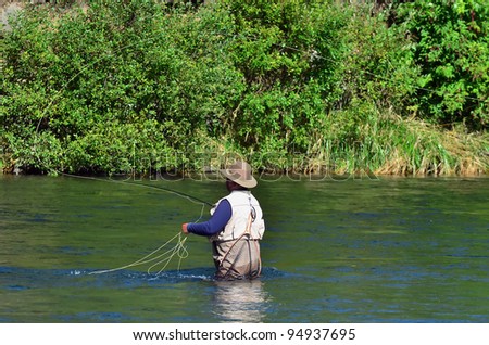 A fisherman fly fishes for Trout fish in Tongariro river near Taupo lake, New Zealand.