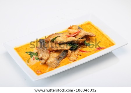Fried fish in spicy curry sauce on white dish