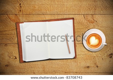 An open notebook with cup of coffee on wooden table