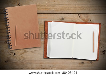 Open leather book with another book on wooden table