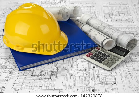 Yellow helmet, calculator, blue folder document and project drawings