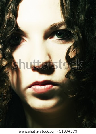 A portrait about a pretty lady with white skin and long brown wavy hair who has a frown look