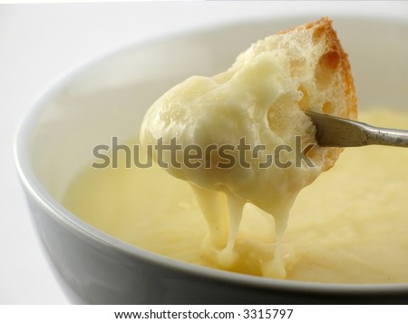 Melted cheese drips from a chunk of fresh bread in cheese fondue dinner.