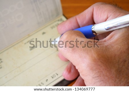 Male hand with pen filling a bank check