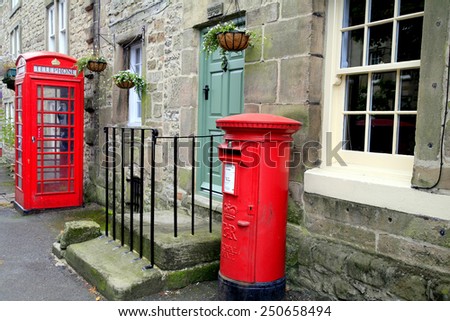 WINSTER, DERBYSHIRE, UK.  CIRCA- SEPTEMBER 18, 2014.  Post and telephone boxes, means of communication, stand on the main street outside a cottage in the village of Winster, Derbyshire.