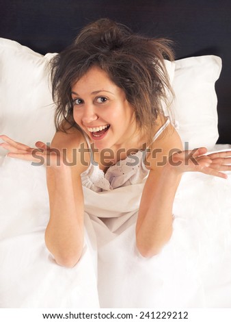 Excited woman in bed with funky hair