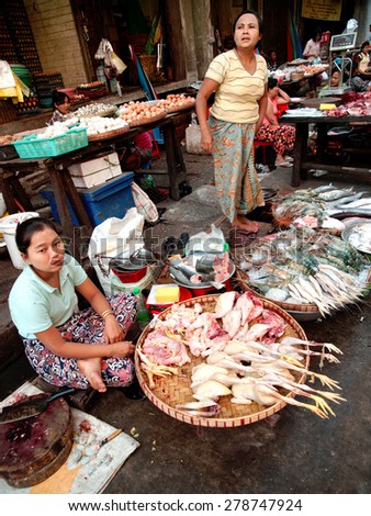Yangon, Myanmar - February 24, 2011 : Young Burmese women selling fresh raw meat in the street market.