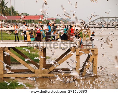 Yangon, Myanmar - February 24, 2011 : Burmese people feeding the hungry seagulls on the pier of Yangon at sunset