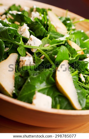 Fresh spinach salad with blue cheese, pears and honey served in a salad bowl, close up