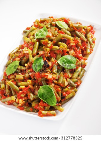 French beans and tomato casserole in large baking dish. Shot from above over white background.