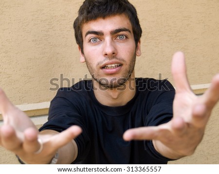 Portrait of a young man begging his girl to stay with him. Arms pointing at camera.