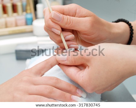 Preparing manicure in a beauty salon. Fixing an artificial nail on finger.