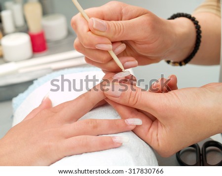Preparing manicure in a beauty salon. Detail on finger and artificial nail.