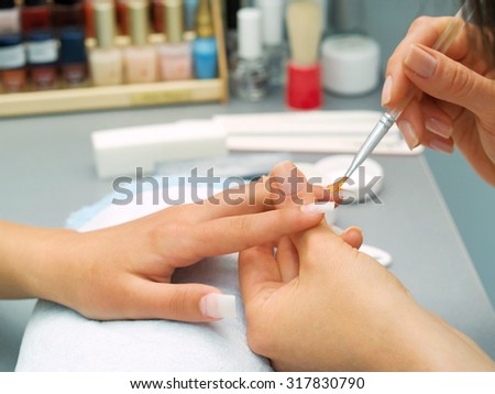 Preparing manicure in a beauty salon. Nail polish bottles on background.