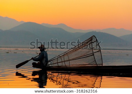Heho, Myanmar - March 02, 2011 : Intha fisherman fishing at sunset in his typical canoe with fishing net