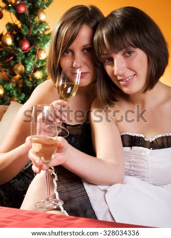 Young women with Chamapgne flutes with Christmas tree behind.