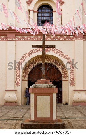 Cross in front of a pink painted church in Chiapas, Mexico
