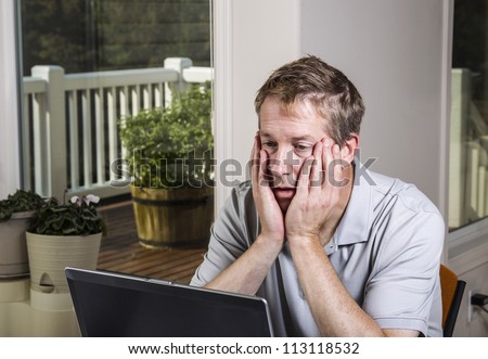 Tired man looking at data results on computer at home