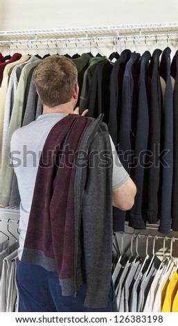 Vertical portrait of mature man in walk-in closet over looking his sweaters for wearing