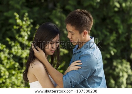 Horizontal photo of a young couple in love with green trees in background