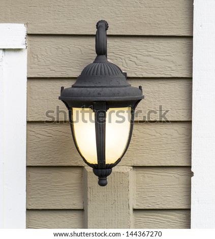 Photo of electric outdoor house lamp on wooden cedar planks attached to house