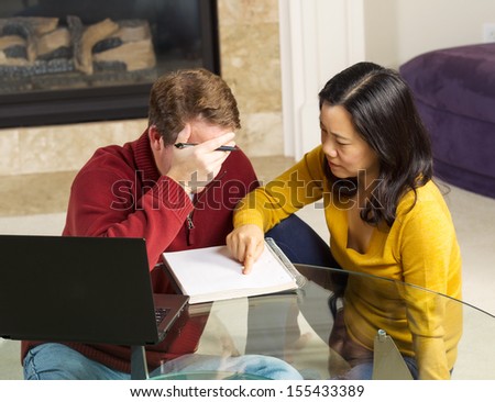 Photo of mature couple displaying urgency while working from home with fireplace in background