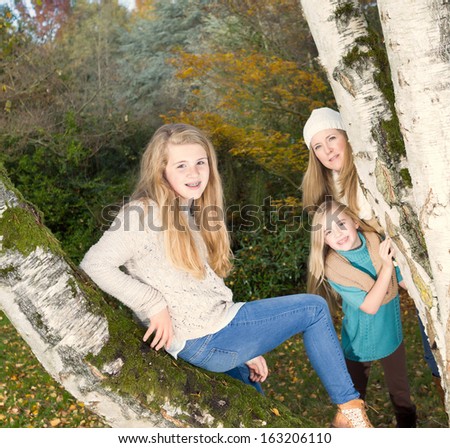 Photo of oldest daughter sitting in middle of tree with mother and younger daughter in background