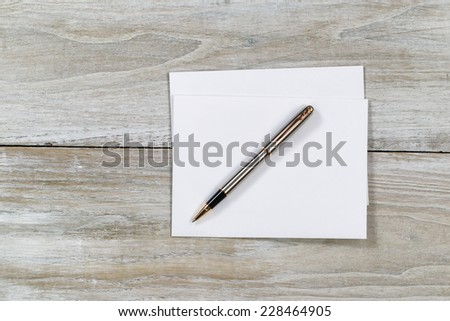 Top view of business envelope and writing pen on rustic white wooden desktop