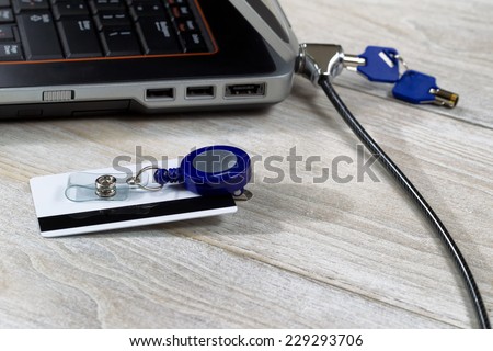 Unsecured security access card with computer, lock, key, and chain in background on rustic white wooden boards