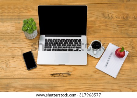 High angled view of simple desktop with mobile computer and cell phone with food and drink.