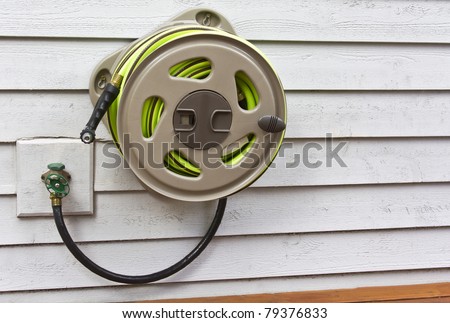 Garden hose, nozzle and  holder on house