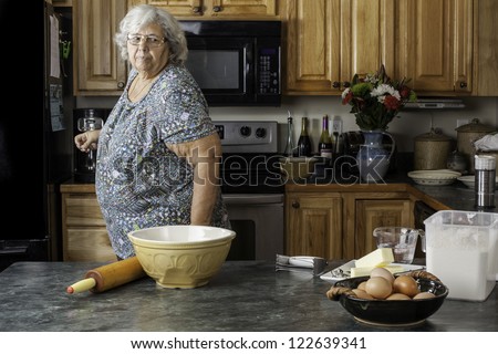 A grandmother or mother in a kitchen looking at supplies getting ready to bake