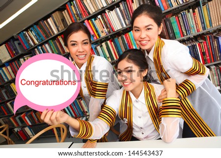 Group of Asian graduate girls with congratulations sign on graduation day.
