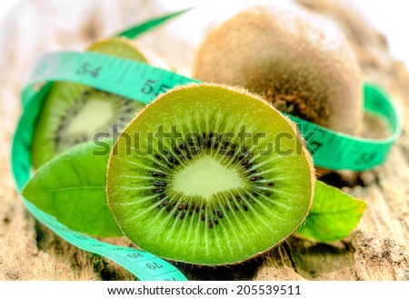 Kiwi fruit with meter tape on old wood.