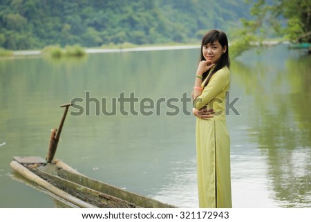 Vietnamese girl standing over Babe lake nation park. She wears yellow \