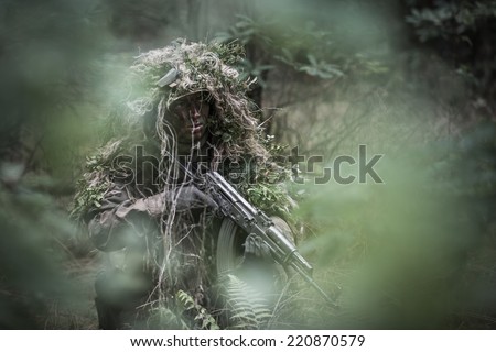 portrait of the soldier wearing ghille suit, hidden in forest