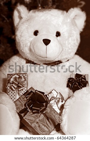 Big white teddy bear holding a presents and sitting at the Christmas tree in black and white