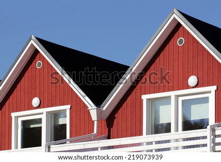 Gables of wooden Scandinavian house  painted in traditional white and red colors against deep blue sky.